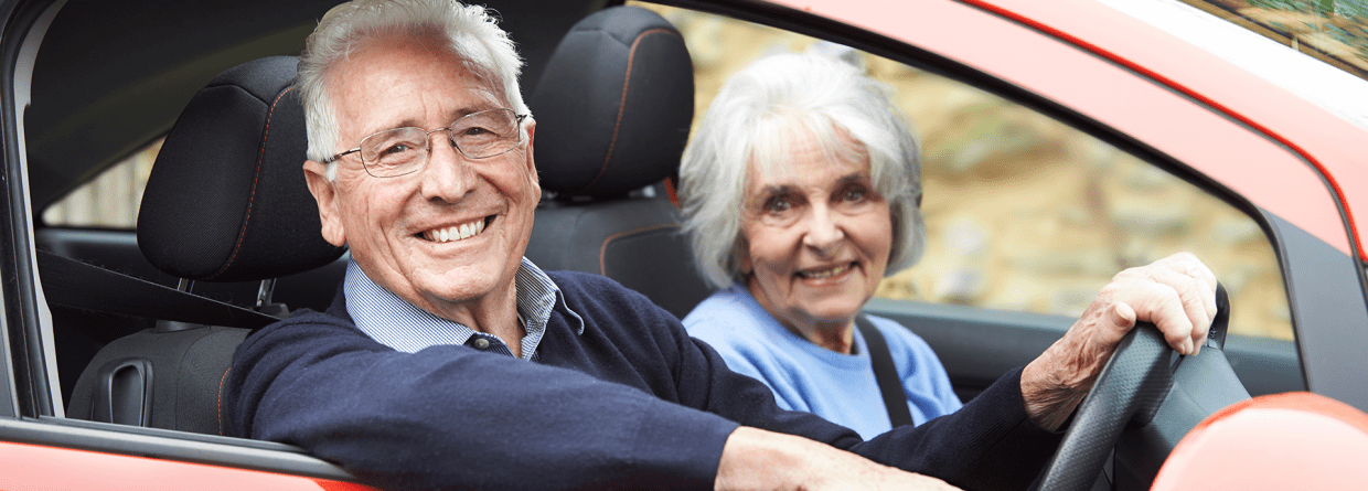 Glimlachend senior stel rijdend in een rode auto