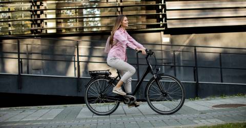 Een vrouw fietst op haar e-bike door de stad
