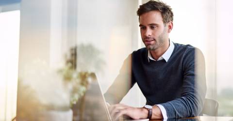 Jonge ondernemer is vanuit huis aan het werk op zijn laptop